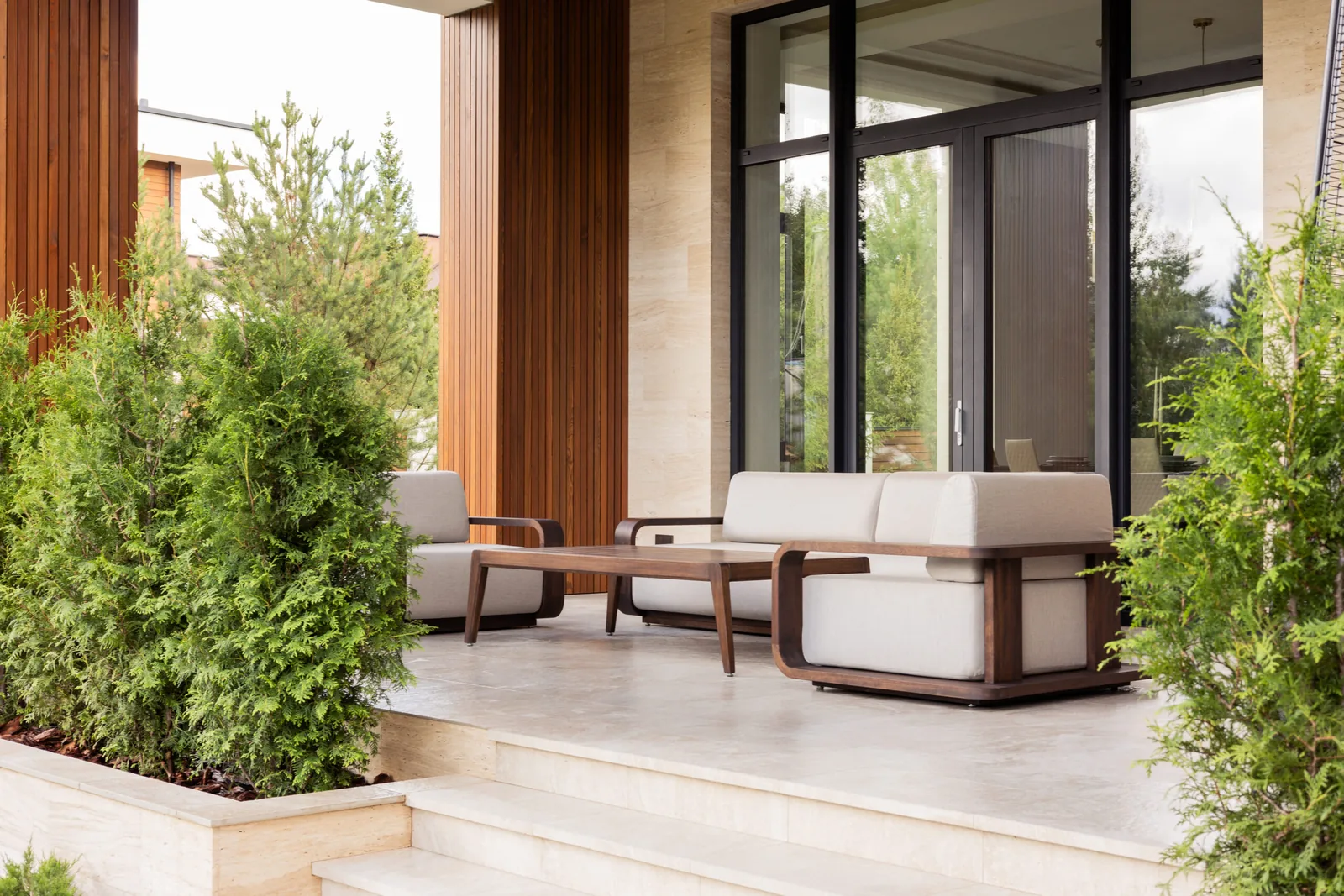 Диван и кресло CASSIA lounge на террасе среди туй